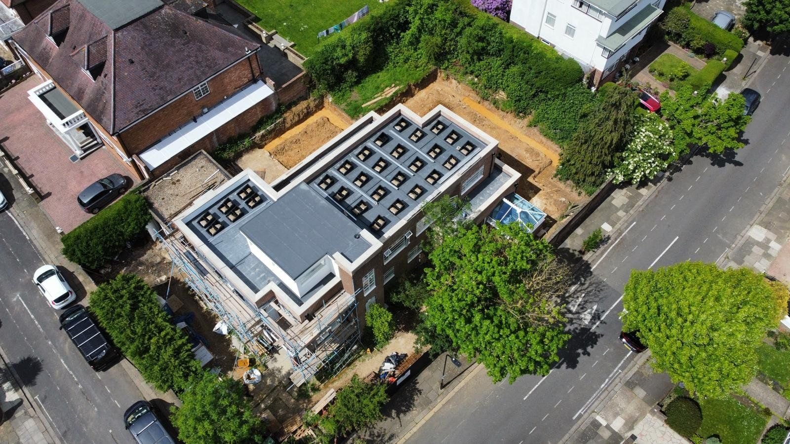 Aerial view from the opposite side of the same flat roof, showing the Fast Tub layout positioned around the rooflights