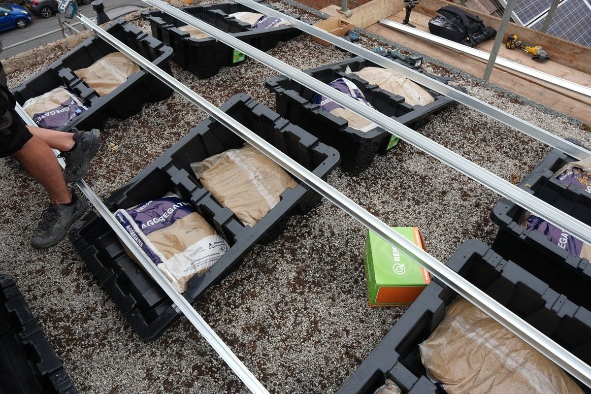 Rows of ballasted Fast Tub units linked by continuous aluminium rails across a flat roof, sharing load rather than working as isolated consoles
