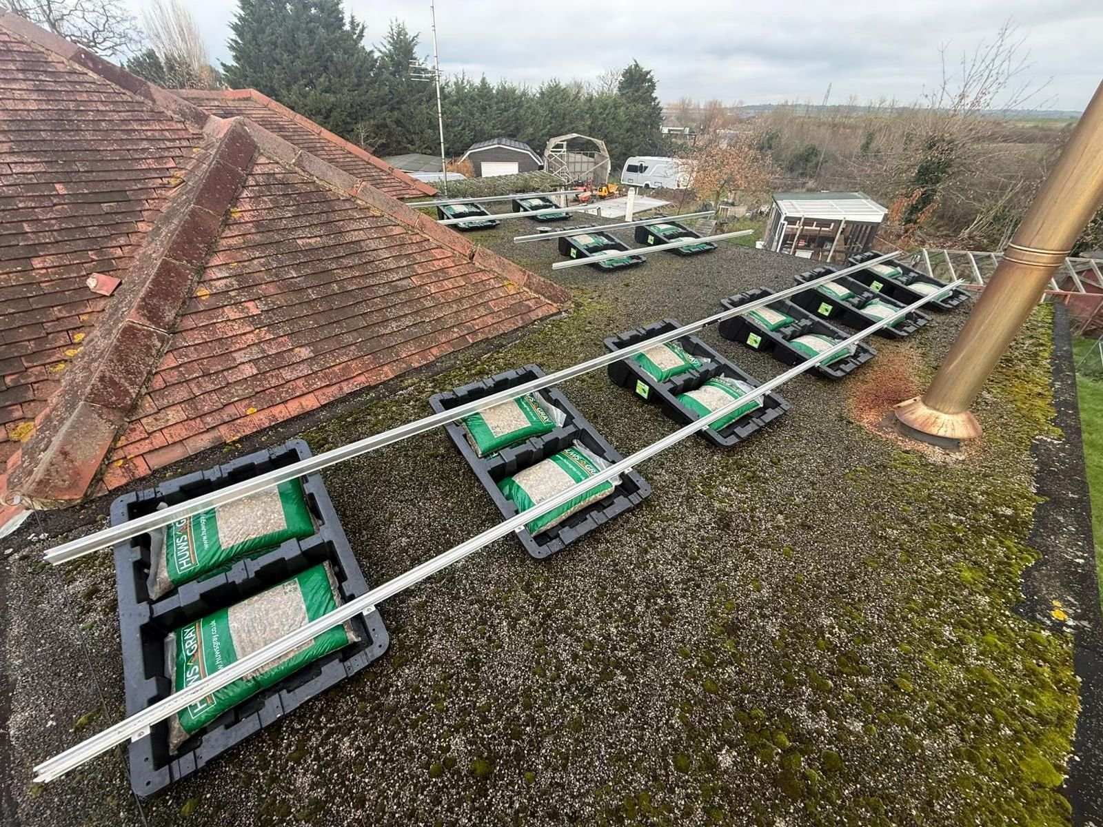 Rows of Fast Tub units on a flat roof, each loaded with gravel ballast bags beneath the rail runs